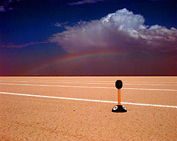 A Fecher on Jafr Desert with a distant rainbow